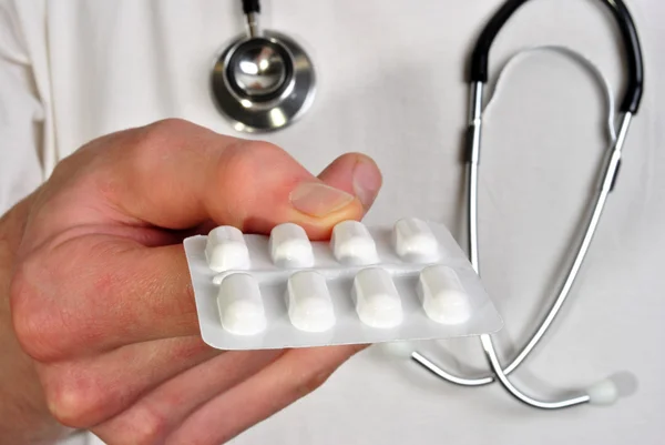 Personelu medycznego w biały tshirt trzyma jakieś tabletki — Zdjęcie stockowe