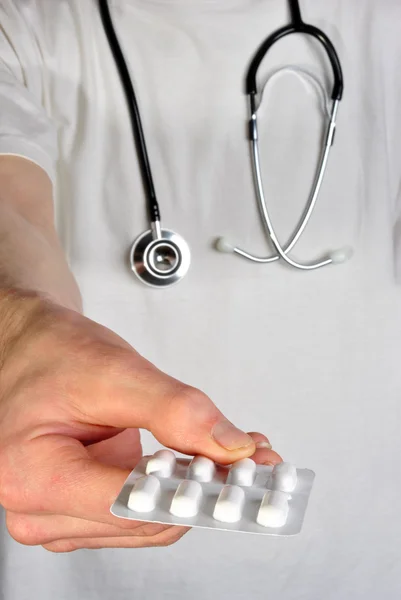 Personal clínico con una camiseta blanca sosteniendo unas pastillas — Foto de Stock