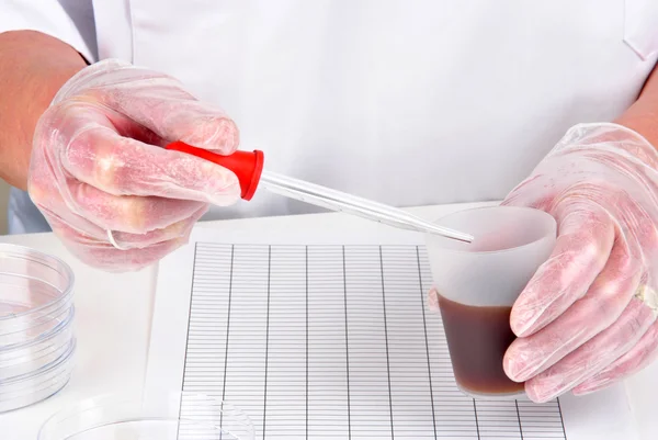 Brown liquid and a pipette in the other hand — Stock Photo, Image