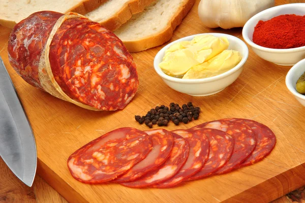 Salame Chorizo e algumas fatias de salame em uma tábua de madeira — Fotografia de Stock