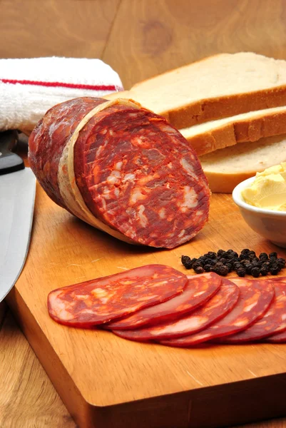 Salame Chorizo e algumas fatias de salame em uma tábua de madeira — Fotografia de Stock