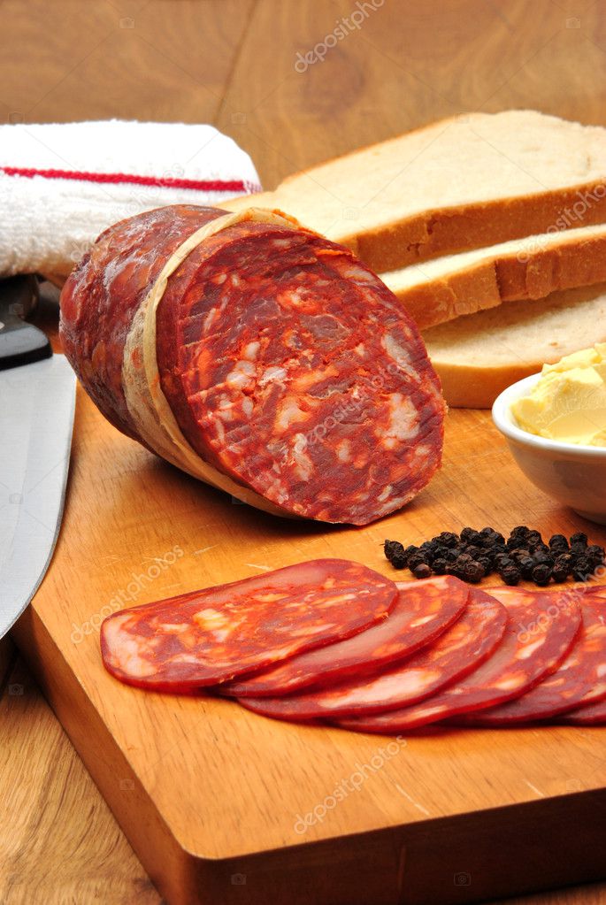 Salami de chorizo y algunas rebanadas de salami en una tabla de madera 2023