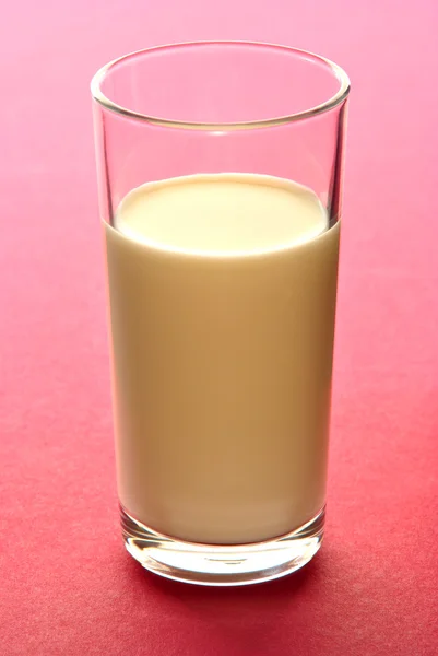Milkshake de banana em um pequeno copo e fundo vermelho — Fotografia de Stock