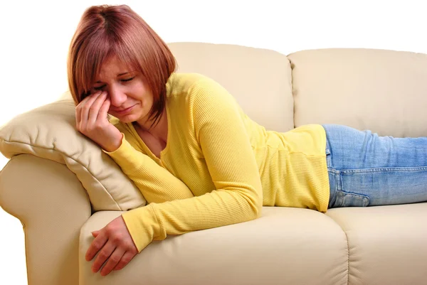 Uma jovem mulher sentada no sofá e infeliz — Fotografia de Stock