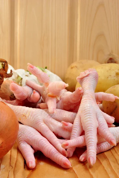 Pés de frango com legumes orgânicos em uma tábua de madeira — Fotografia de Stock