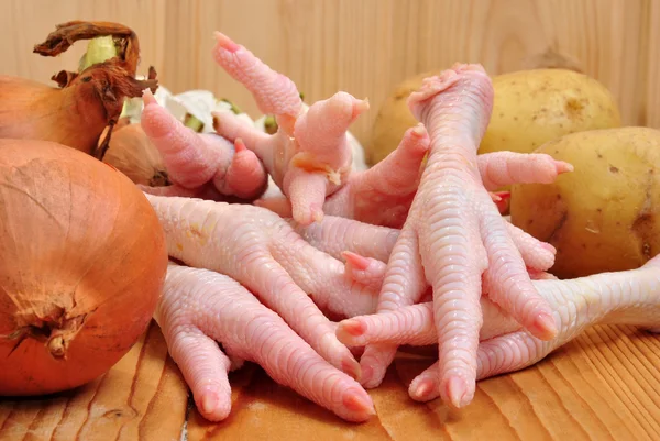 Chicken feet with organic vegetables on a wooden board — Stock Photo, Image