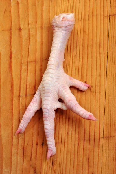 Een kip voet op een houten bord — Stockfoto