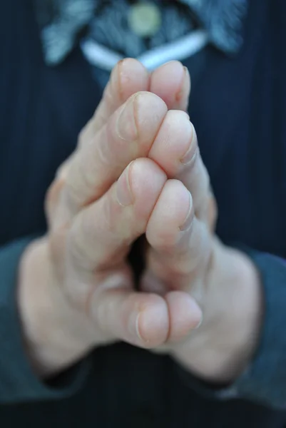 stock image Praying hands of an older person with a dark blue sweater