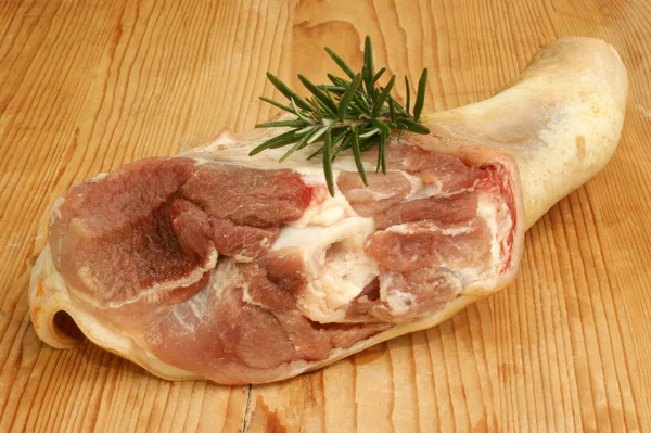 Nudillo crudo de cerdo con romero sobre una tabla de madera —  Fotos de Stock