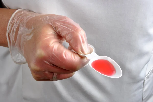 Personnel soignant avec gant jetable et médicament rouge — Photo