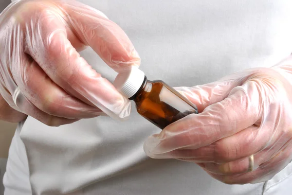 Медицинские работники с одноразовыми перчатками открывают бутылку с таблетками — стоковое фото
