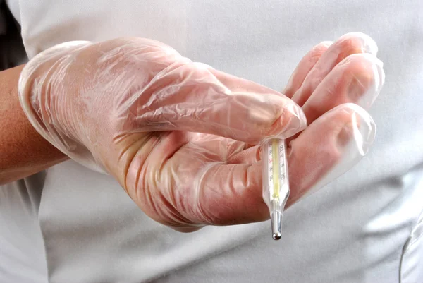 Medical staff keeps thermometer with disposable glove — Stock Photo, Image