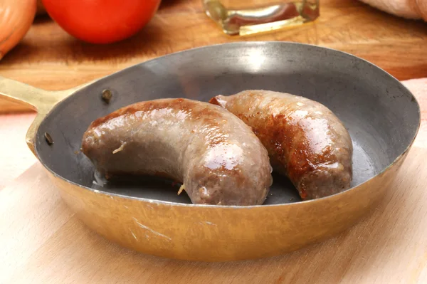 Two home made sausages in a brass pan — Stock Photo, Image