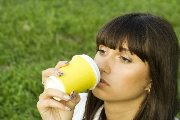 Kvinna i en park som dricker kaffe — Stockfoto