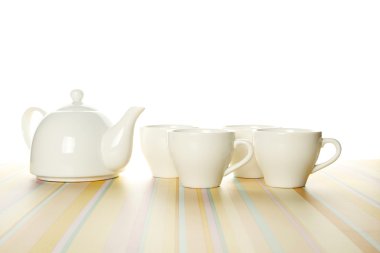 A set of four white cups and a teapot on a light striped background. The upper part of the photo is isolated clipart