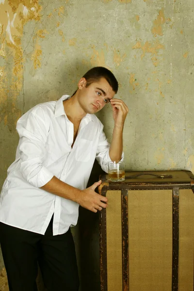 英俊的年轻男子 在旧的房间基于旧箱子旁边他杯威士忌 — 图库照片