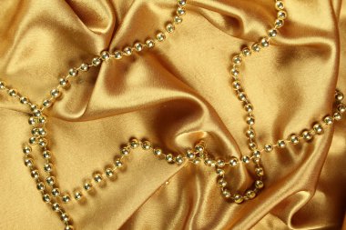 Background of gold cloth on which lay the golden beads clipart