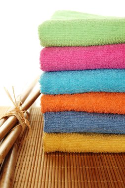 renkli banyo havlusu bir sürü birbiri üzerinde yığılmış. bir ahşap zemine, yan yana bambu sopalarla yalan. izole