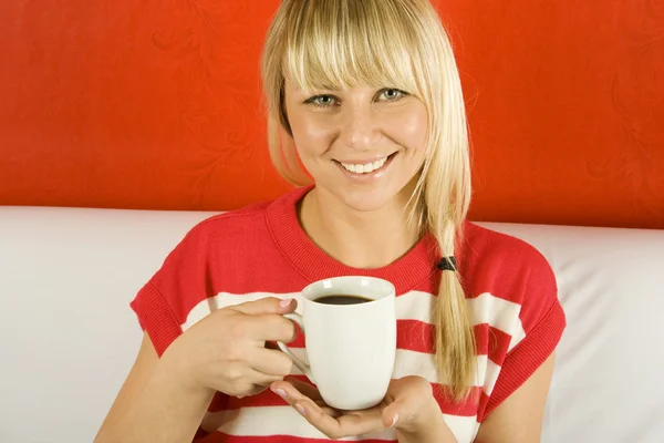 美丽的年轻女子坐在沙发上用白色马克杯喝咖啡 — 图库照片