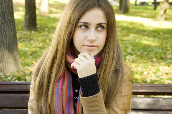 Piękna młoda kobieta siedzi na ławce — Zdjęcie stockowe