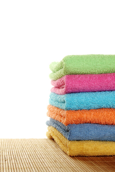 Lots of colorful bath towels stacked on each other. Isolated