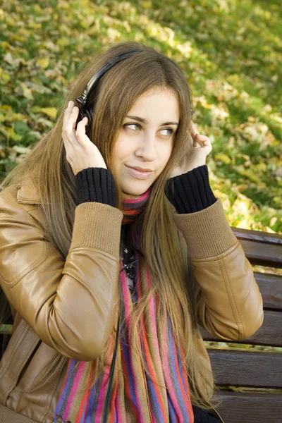 Ung kvinna med hörlurar i parken — Stockfoto
