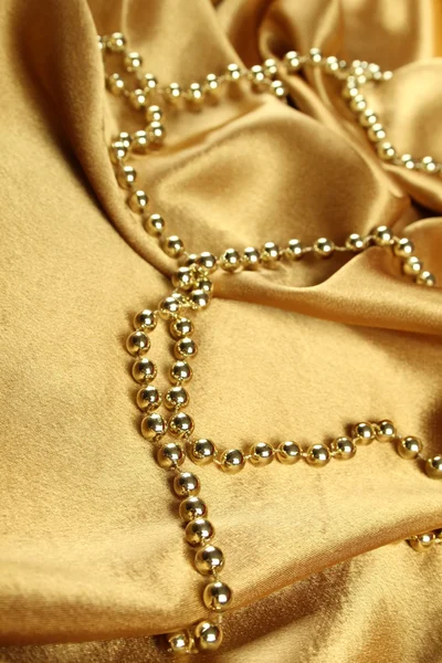 ゴールドの布が横たわっていたゴールド ビーズの背景 — ストック写真