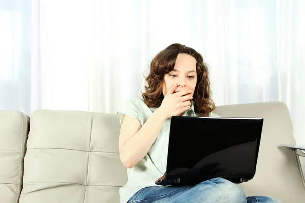 Mladá žena na gauči s notebookem — Stock fotografie