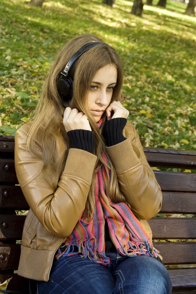 Aantrekkelijk meisje in park luistert naar muziek — Stockfoto