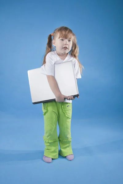 The little girl is holding computer on blue — Stock Photo, Image