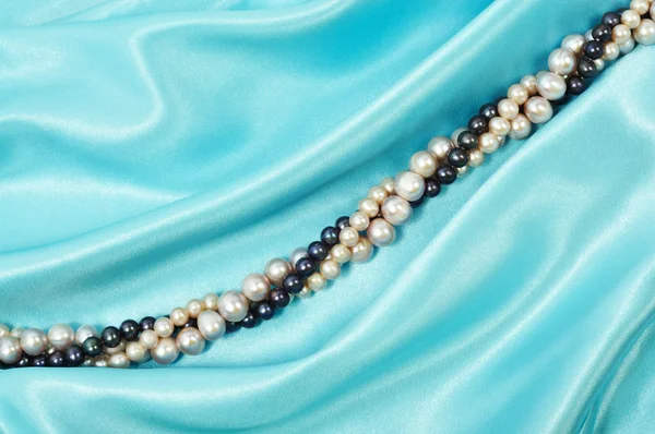 带上它的珍珠项链蓝色丝绸背景 — 图库照片