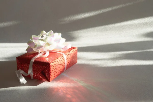 Gift in a red paper on a light background — Stock Photo, Image