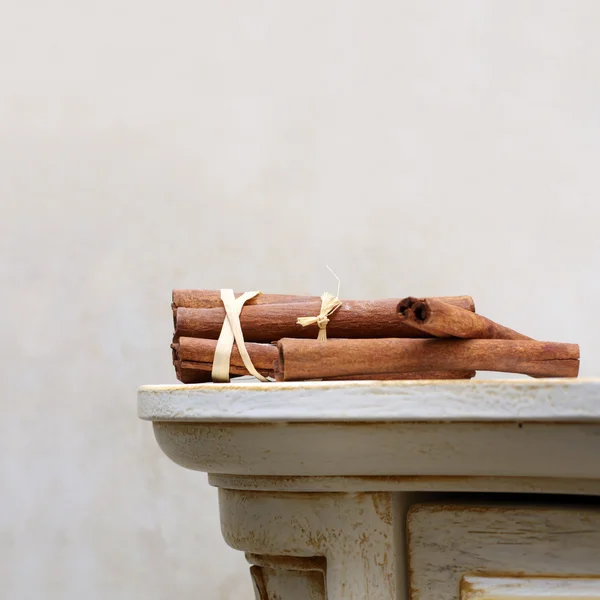 Brown cinnamon sticks lie on the vintage wooden desk — Stock Photo, Image