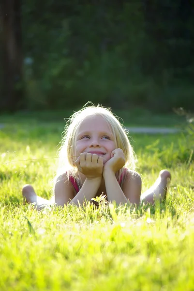 Bekymmerslöst glad liten flicka på gräs. ljuseffekt — Stockfoto