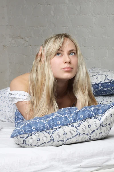 美しい金髪の女性のベッドで横になっていると見上げます。穏やかな朝 — ストック写真