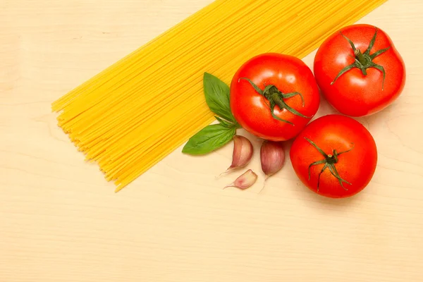 Makarna, sarımsak, domates ve fesleğen ahşap oyun tahtası — Stok fotoğraf
