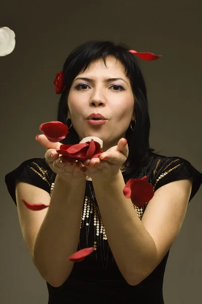 Vackra passionerad kvinna blåser på rosenblad — Stockfoto