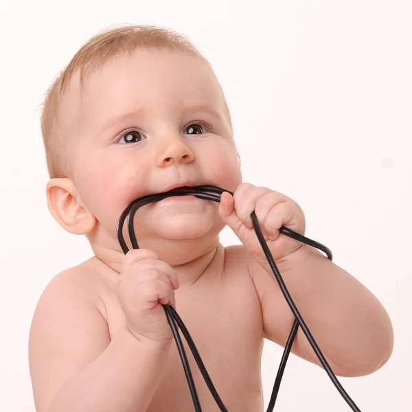 Down the wire! Baby bites computer wires — Stock Photo, Image