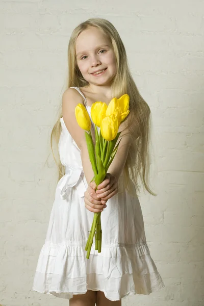Ung leende flicka med gula blommor — Stockfoto