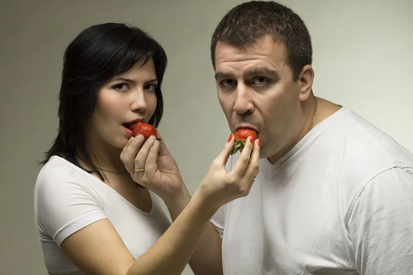 Amantes jovens - homem e mulher comem morango vermelho — Fotografia de Stock