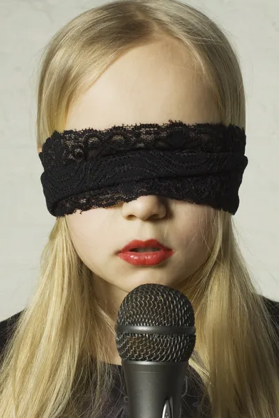 Girl with a black lace blindfold and a microphone. Mystery — Stockfoto