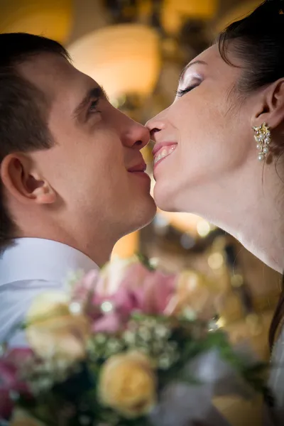 Bela noiva jovem beijando noivo em ambiente interno — Fotografia de Stock