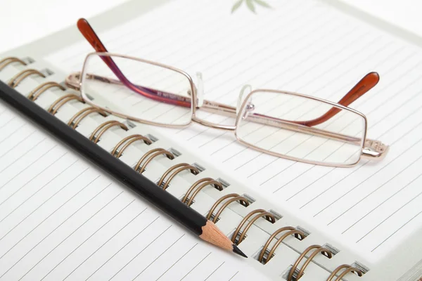 Een dagboek, potlood en glazen — Stockfoto