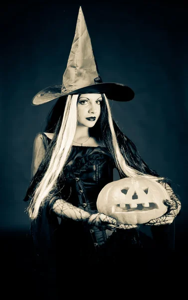 Halloween-Hexe mit geschnitztem Kürbis vor dunklem Hintergrund — Stockfoto