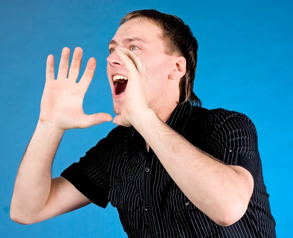 Young man shouting with hands cupped to his mouth Stock Image