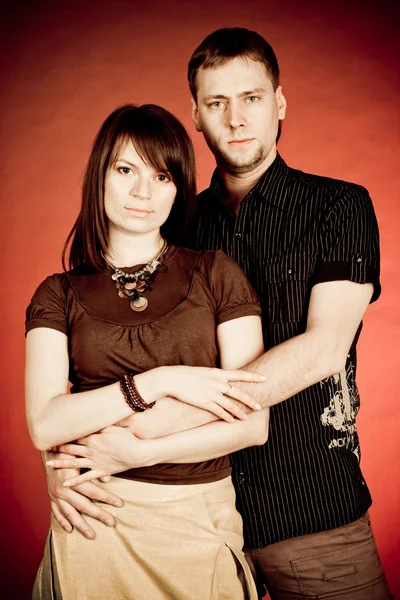 Stock image Portrait of a happy young couple hugging each other against red