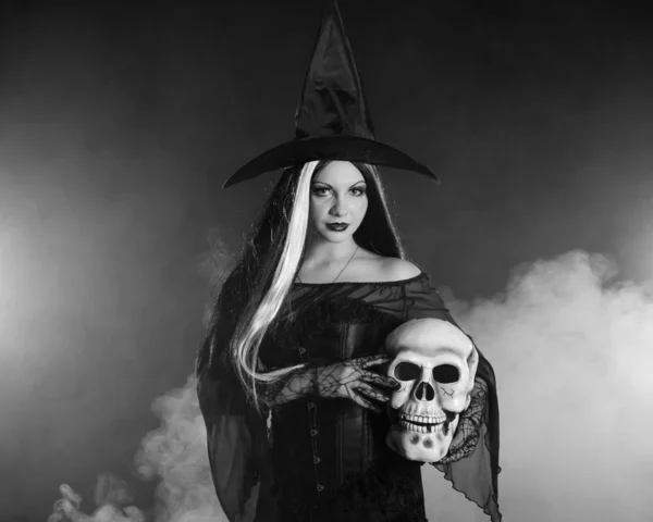Halloween heks met een schedel op zwarte achtergrond met rook — Stockfoto