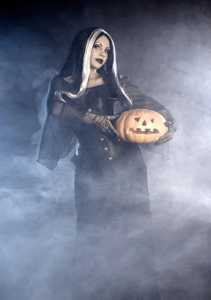Bruxa halloween com uma abóbora. — Fotografia de Stock
