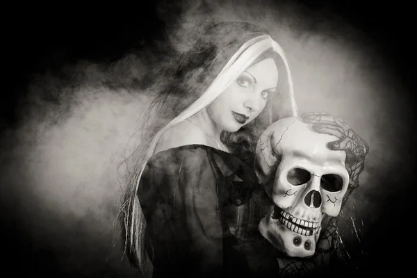Halloween sorcière avec un crâne sur fond noir avec de la fumée — Photo