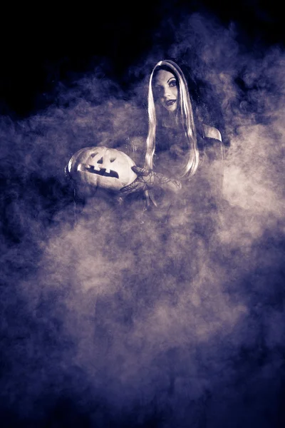 Portrait Halloween witch with a pumpkin. Stock Photo